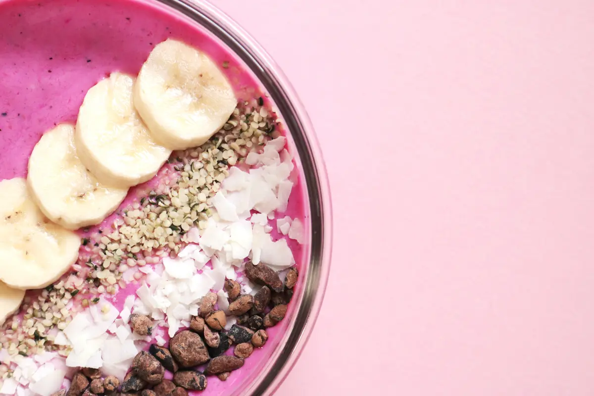 Uma tigela de smoothie com banana e granola, fotografada de cima.