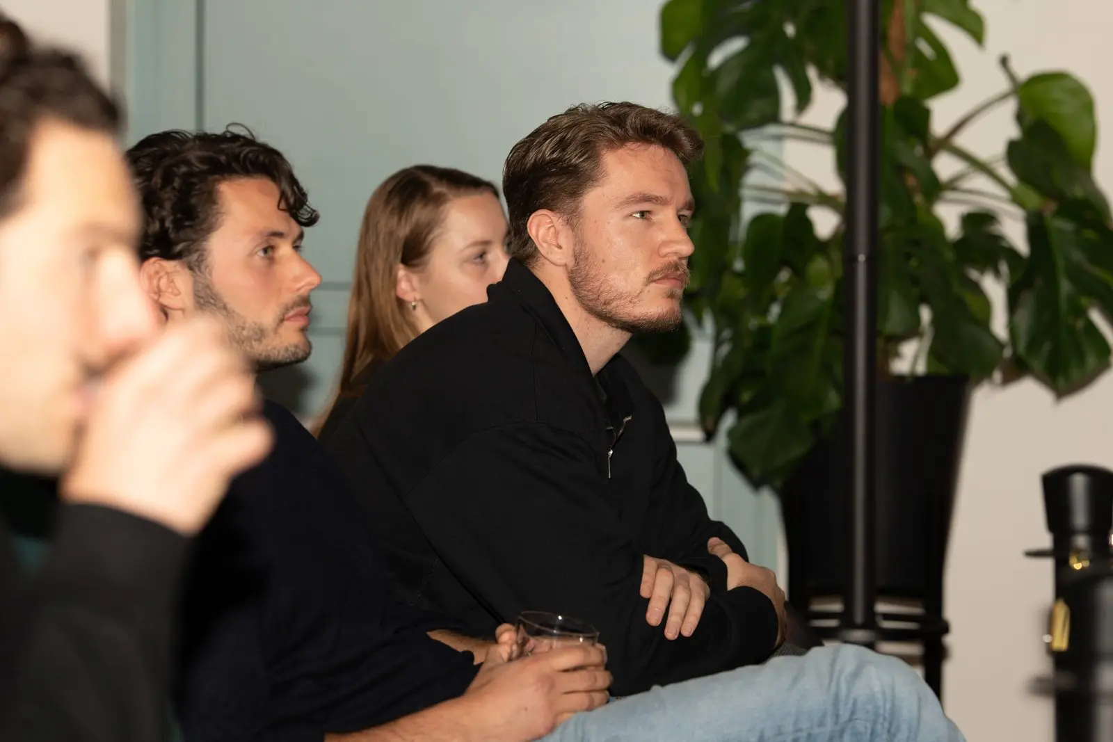 Vier mensen luisteren naar een presentatie.