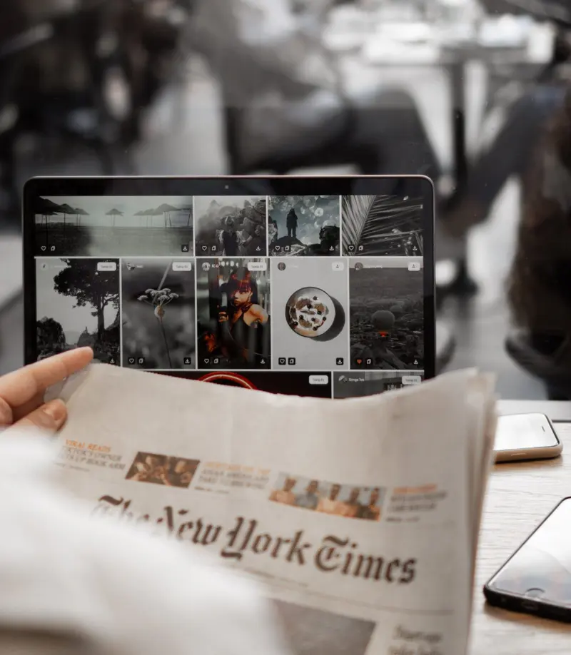 An open newspaper and a tablet displaying news photos side by side.