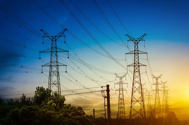 High-voltage pylons and cables against an evening sky.