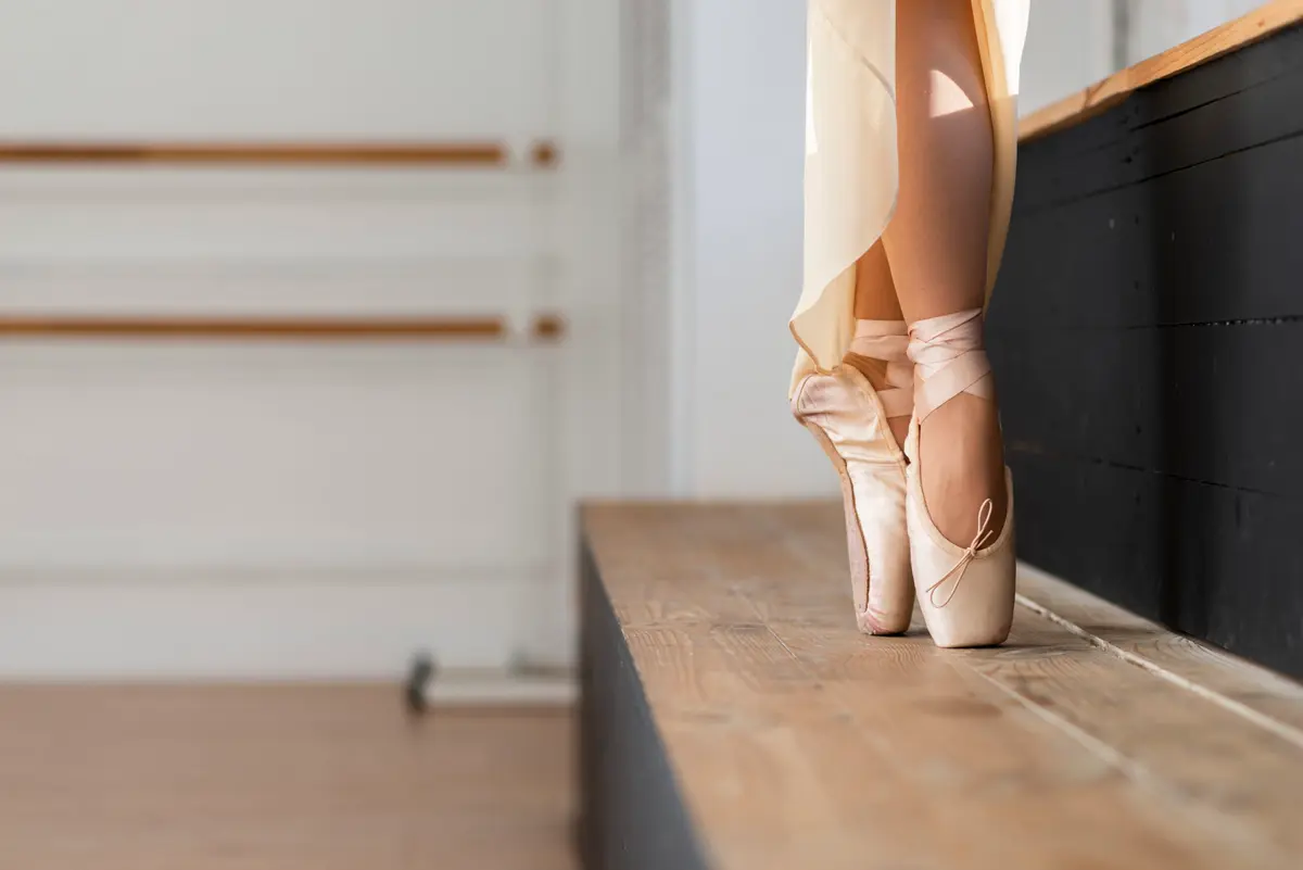 De voeten van een balletdanser op spitzen bij de barre.
