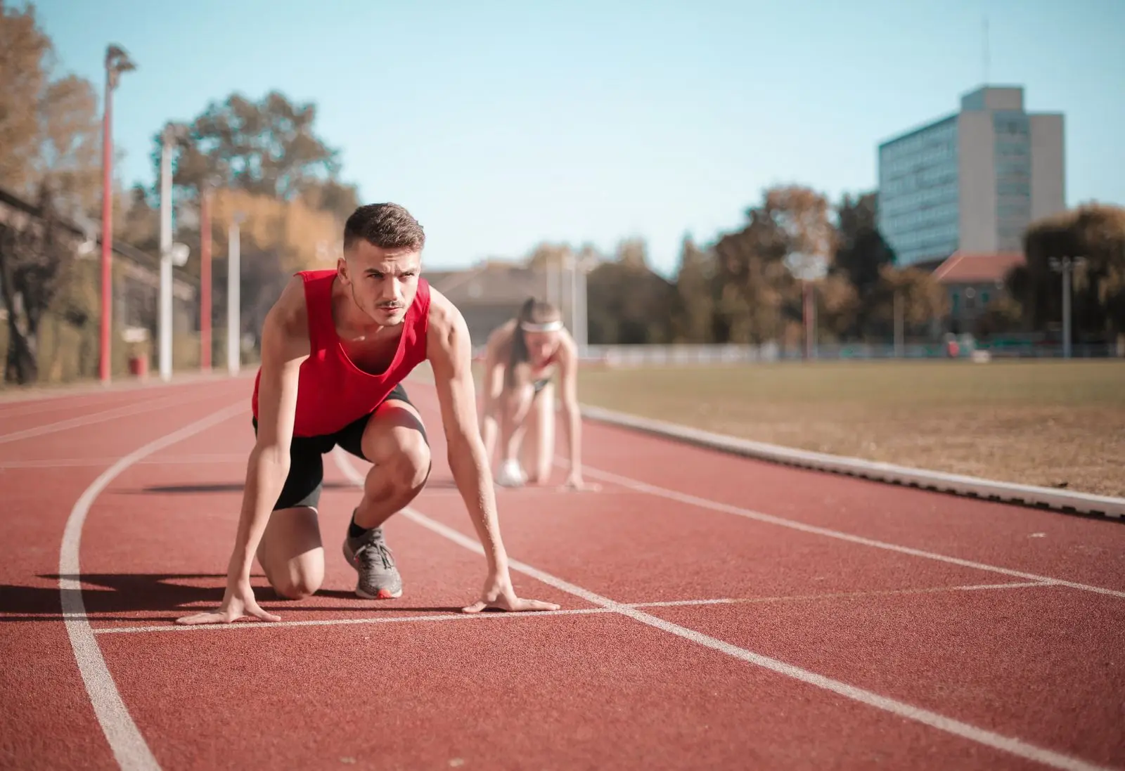 Sprinter in startpositie op een atletiekbaan