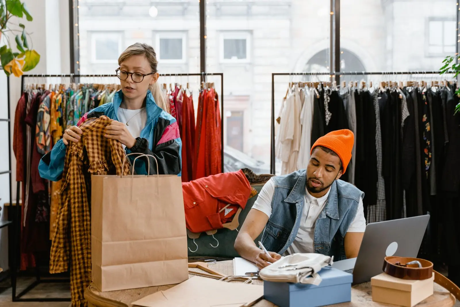Twee medewerkers van een kledingwinkel pakken bestellingen van klanten in
