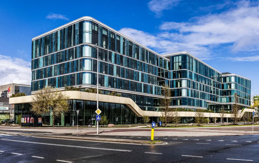 Een modern kantoorgebouw met een glazen gevel langs de weg.