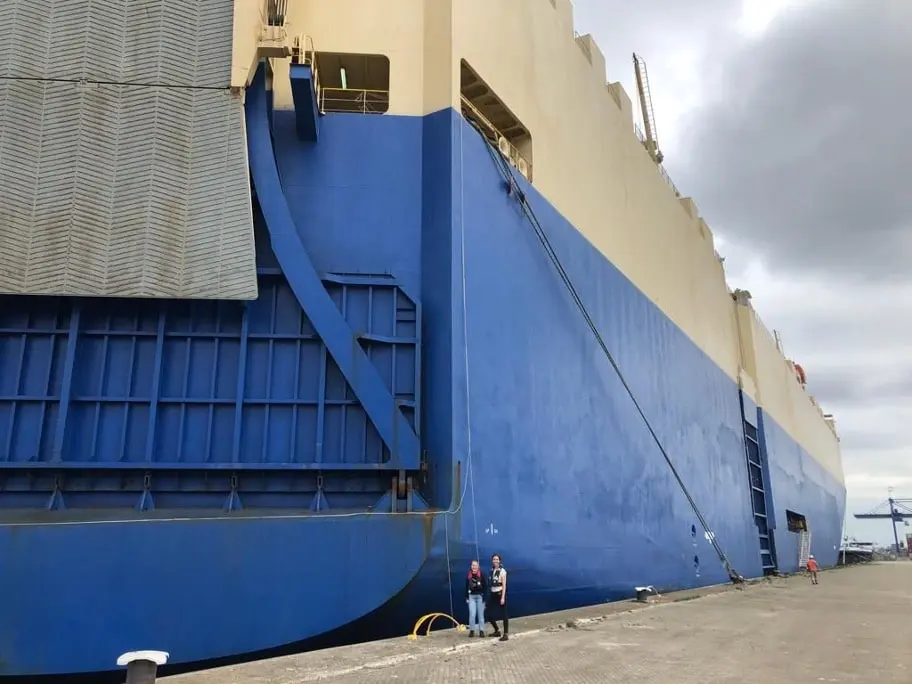 A blue car carrier is moored at the quay.