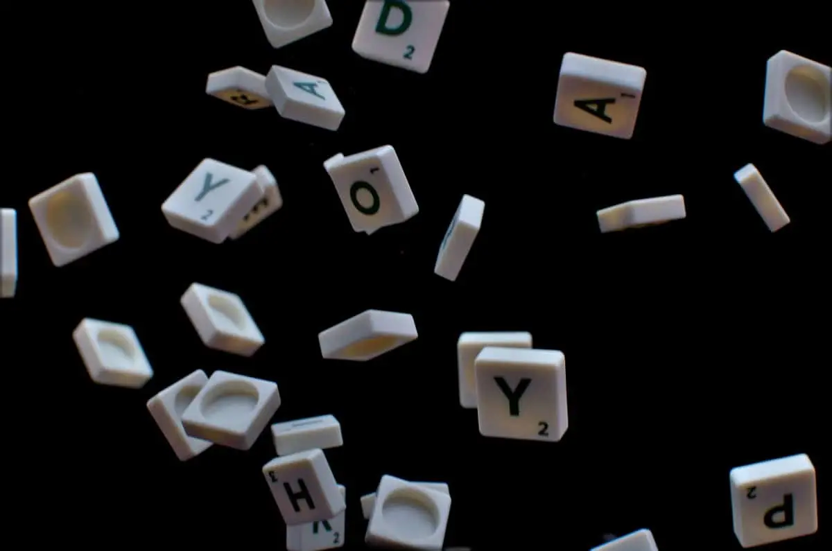 Peças de Scrabble soltas sobre um fundo preto.