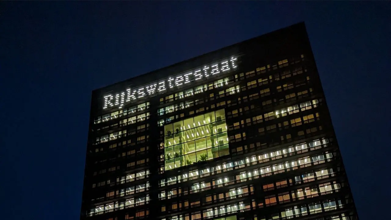 The Rijkswaterstaat office with its façade lit up in the evening.