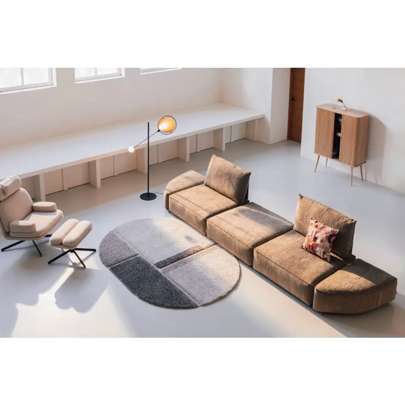 Uma sala luminosa com um sofá bege, um candeeiro de pé e um tapete redondo.