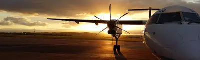 Um avião a hélice na placa de estacionamento ao pôr do sol.